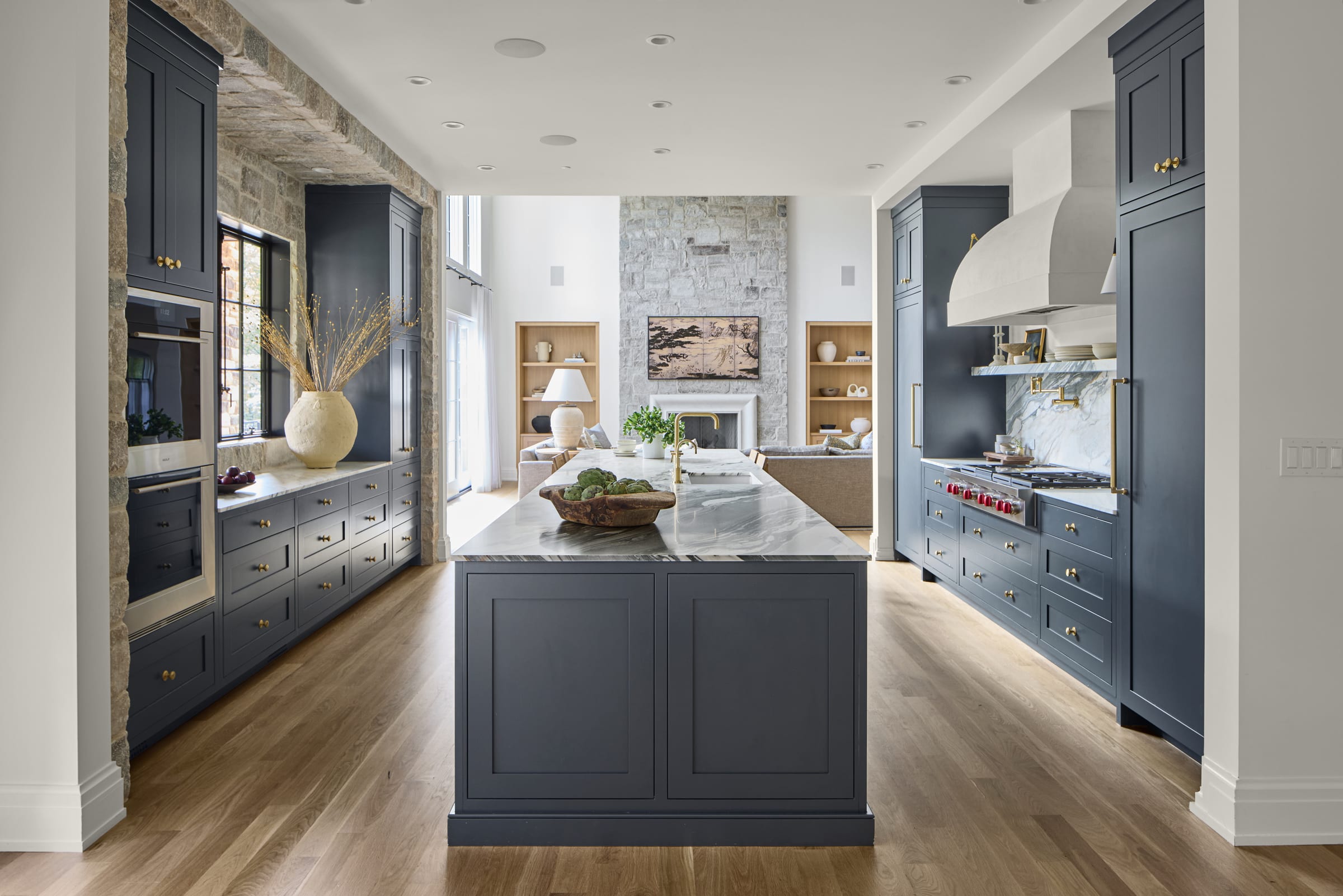 Custom blue kitchen with marble counters, warm oak floors and a central island in a modern organic home in Mendham, New Jersey by Ellie Mroz Design.