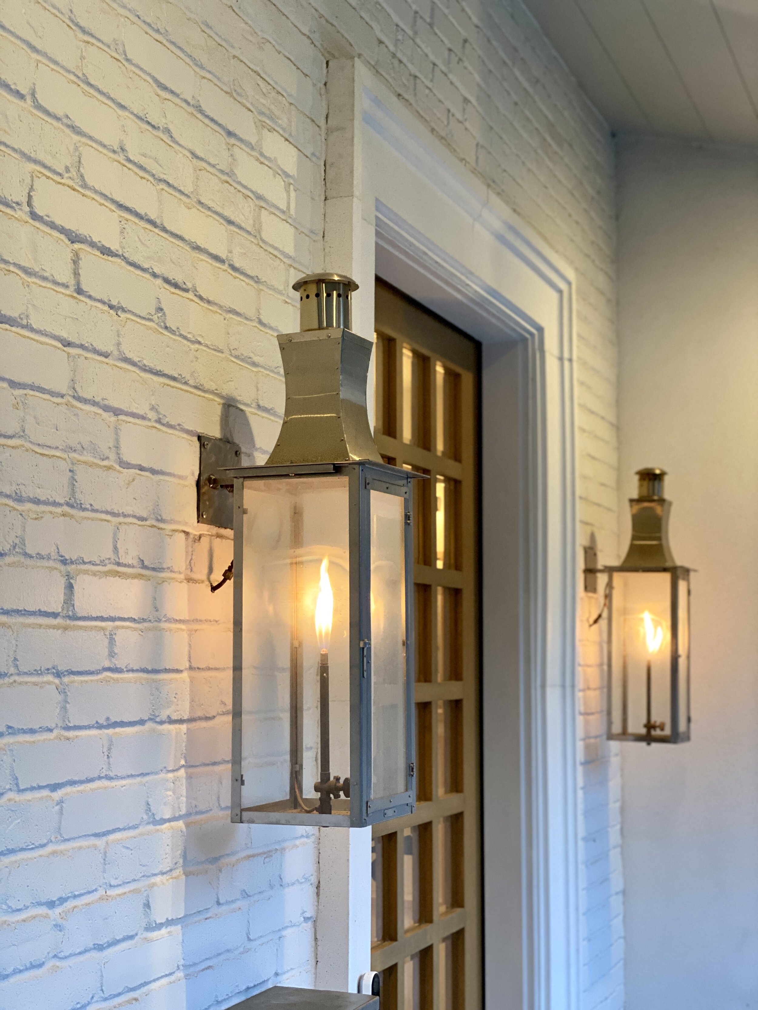 Brass lantern sconces mounted on a brick facade with white trim in a Westfield, NJ new-construction home by Ellie Mroz Design.