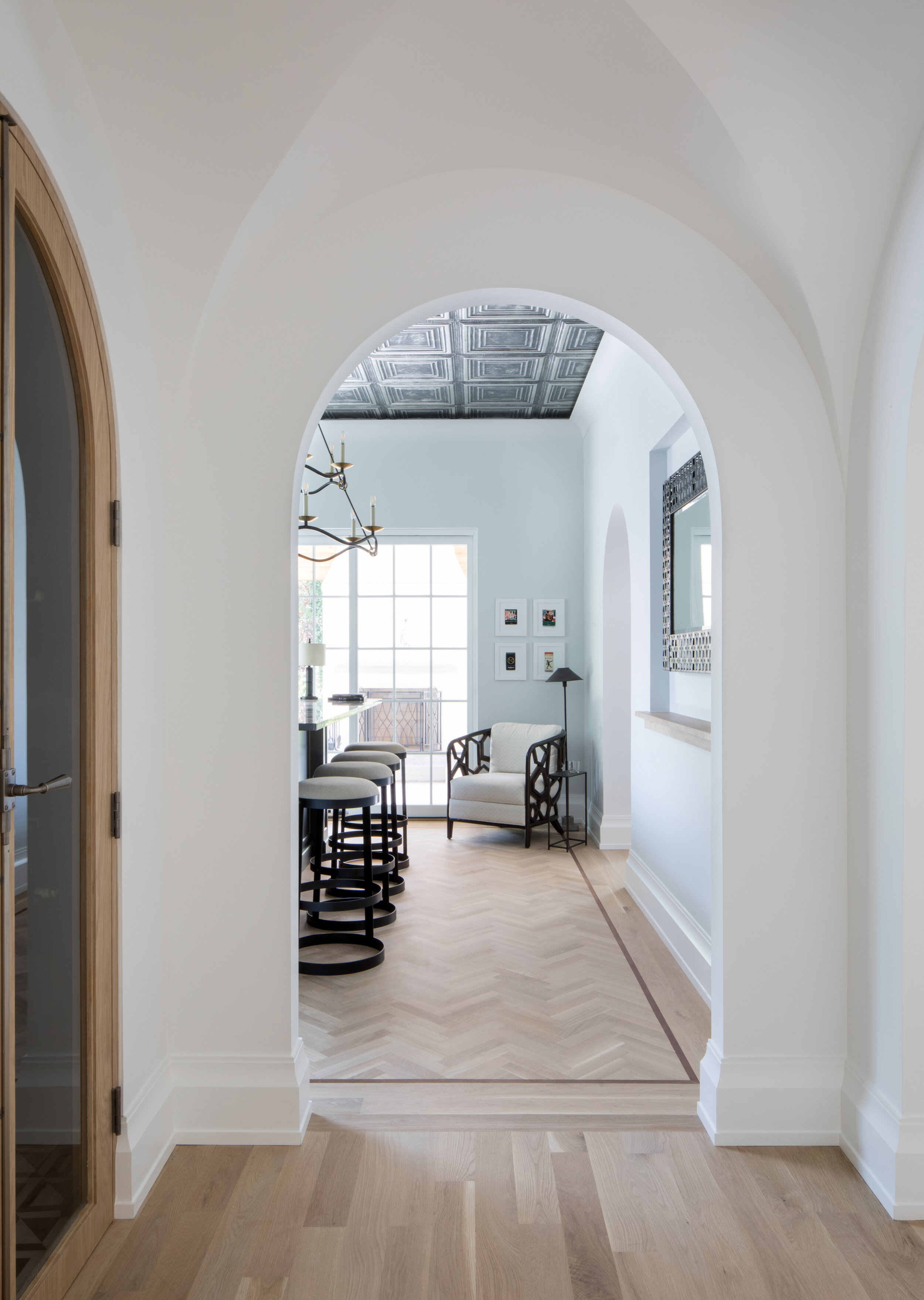Arched plaster openings framing a view through to the dining room, with a pressed tin ceiling beyond in a Westfield, NJ home by Ellie Mroz Design.
