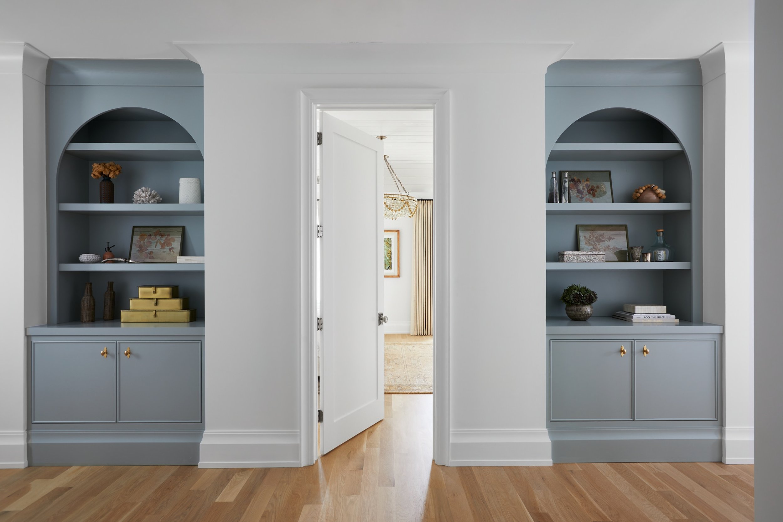 Blue built-in bookshelves flanking a doorway in an upstairs hallway of a Westfield, NJ new-construction home by Ellie Mroz Design.